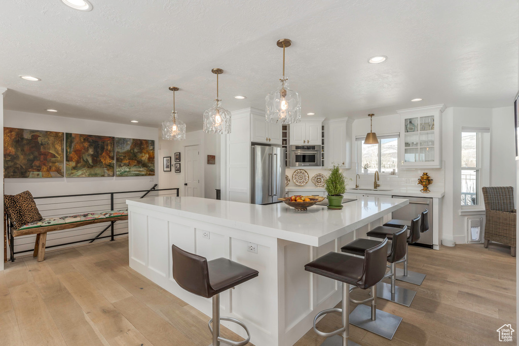 Kitchen featuring appliances with stainless steel finishes, light wood finished floors, recessed lighting, light countertops, and white cabinetry