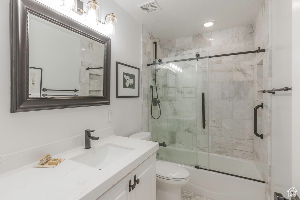 Bathroom featuring toilet, vanity, enclosed tub / shower combo, and recessed lighting