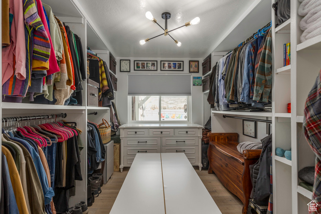 Spacious closet featuring a chandelier and light wood finished floors