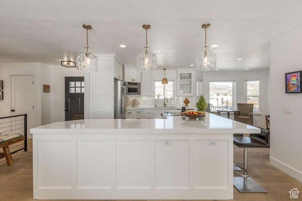 Kitchen with a sink, white cabinets, stainless steel refrigerator, healthy amount of natural light, and recessed lighting