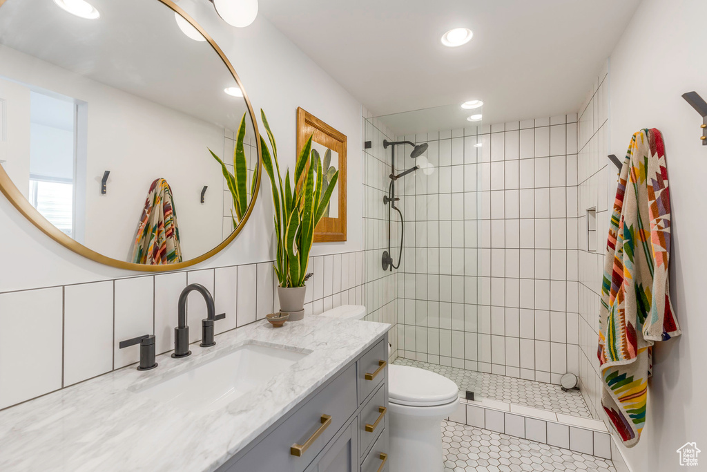 Bathroom featuring toilet, tiled shower, vanity, recessed lighting, and tile patterned floors