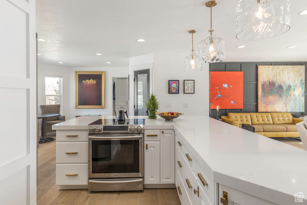 Kitchen featuring electric stove, light countertops, light wood finished floors, white cabinets, and recessed lighting
