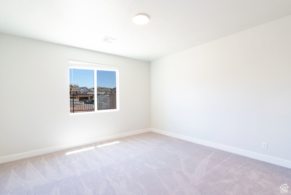 Empty room featuring visible vents, baseboards, and light carpet