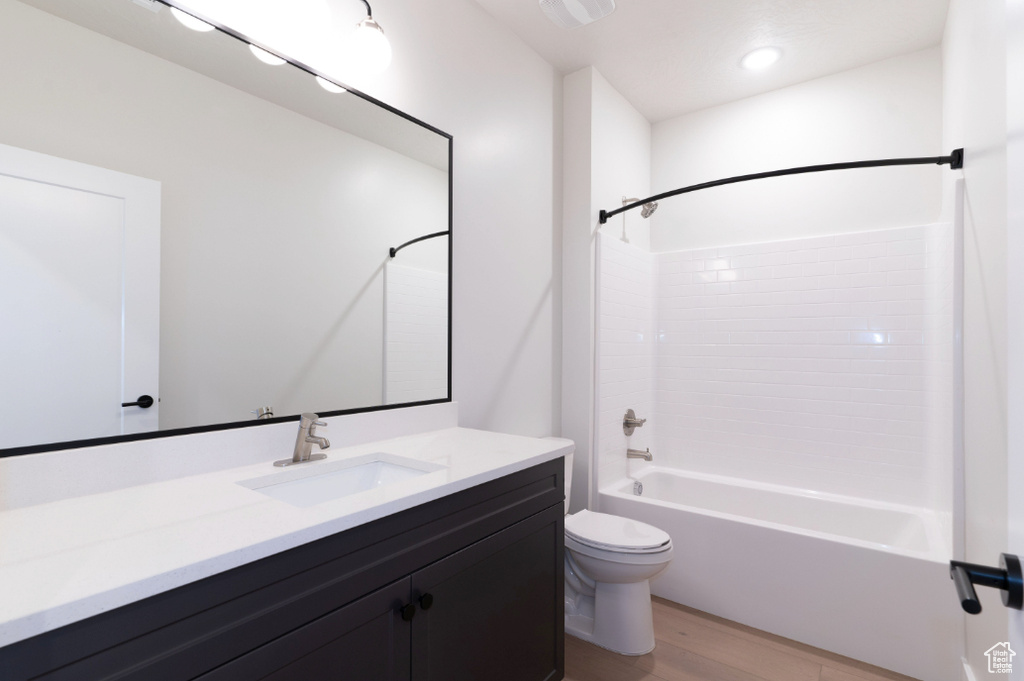Full bath featuring toilet, wood finished floors, vanity, and bathtub / shower combination