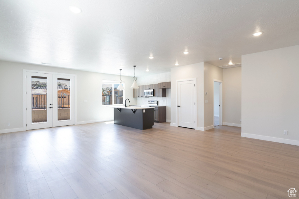 Unfurnished living room with french doors, a sink, baseboards, and recessed lighting