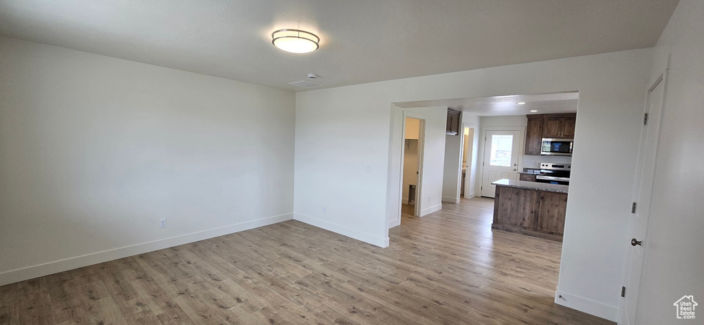 Unfurnished living room with light wood finished floors and baseboards