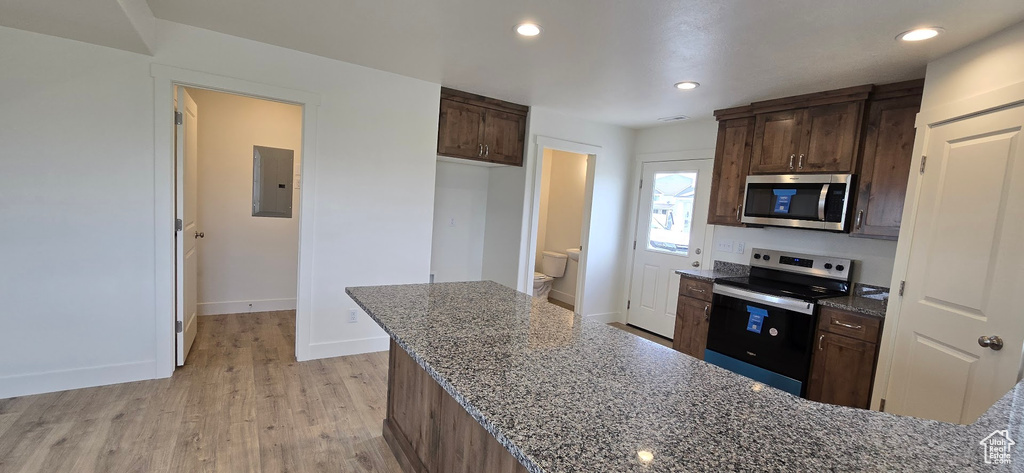 Kitchen featuring appliances with stainless steel finishes, electric panel, dark stone counters, and recessed lighting