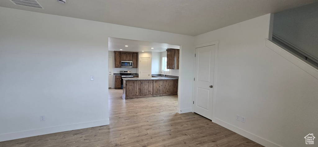 Kitchen featuring stainless steel microwave, baseboards, light wood finished floors, recessed lighting, and a peninsula