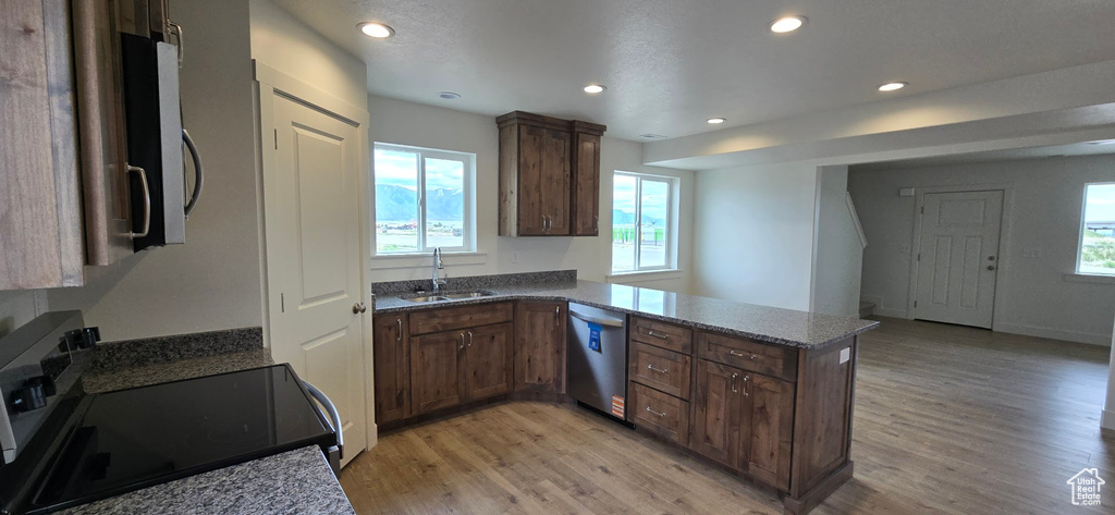 Kitchen with dishwasher, black electric range oven, a sink, light wood-style flooring, and plenty of natural light