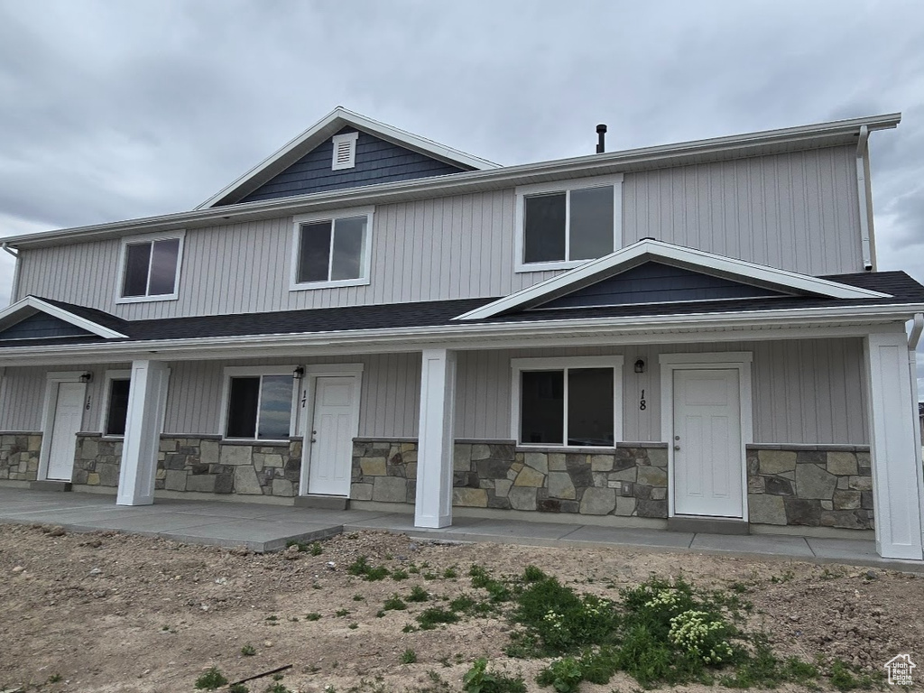 Back of property featuring covered porch and stone siding