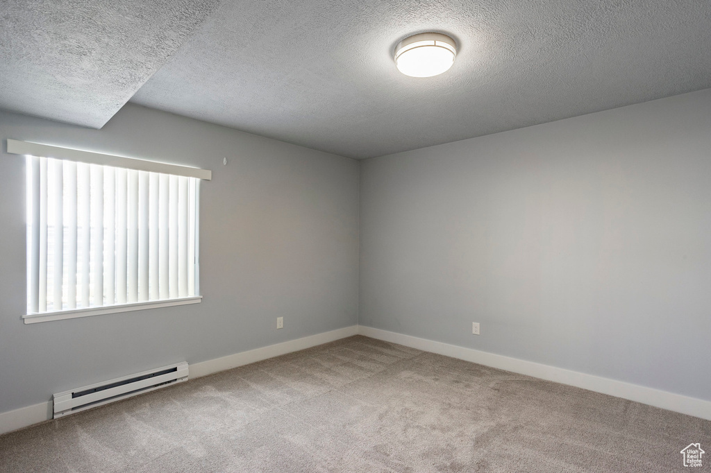 Unfurnished room with baseboards, a textured ceiling, carpet flooring, and baseboard heating