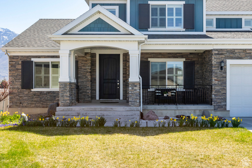 Entrance to property with a yard, stone siding, and covered porch