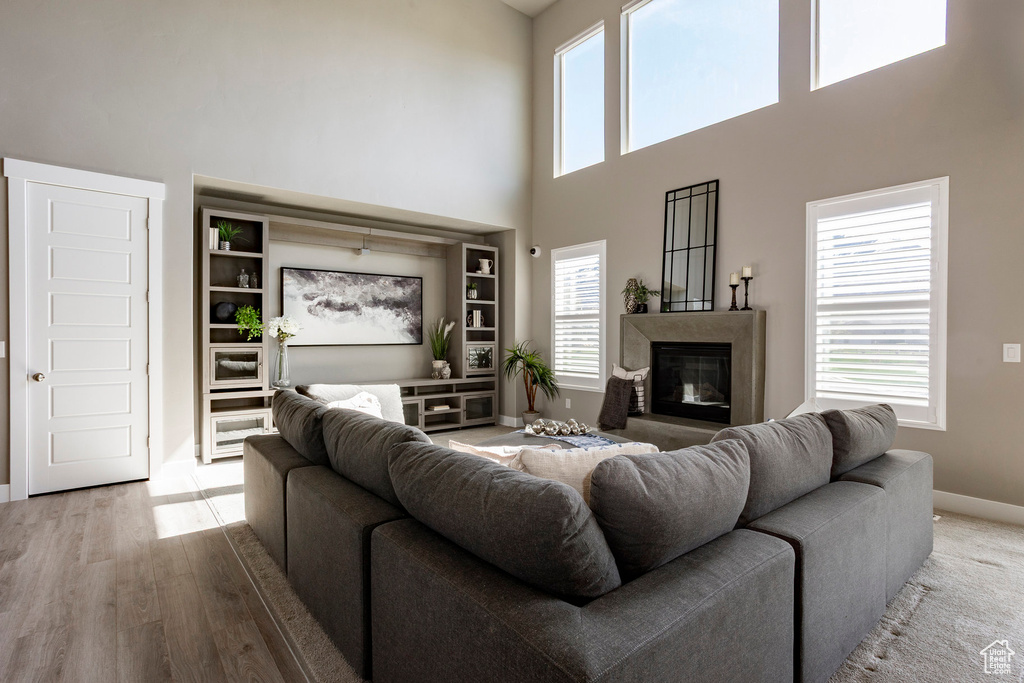Living room with a high end fireplace, a towering ceiling, baseboards, and wood finished floors