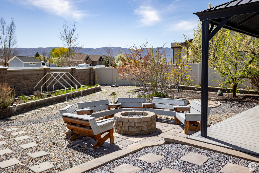 View of patio featuring a fire pit, a fenced backyard, and a mountain view