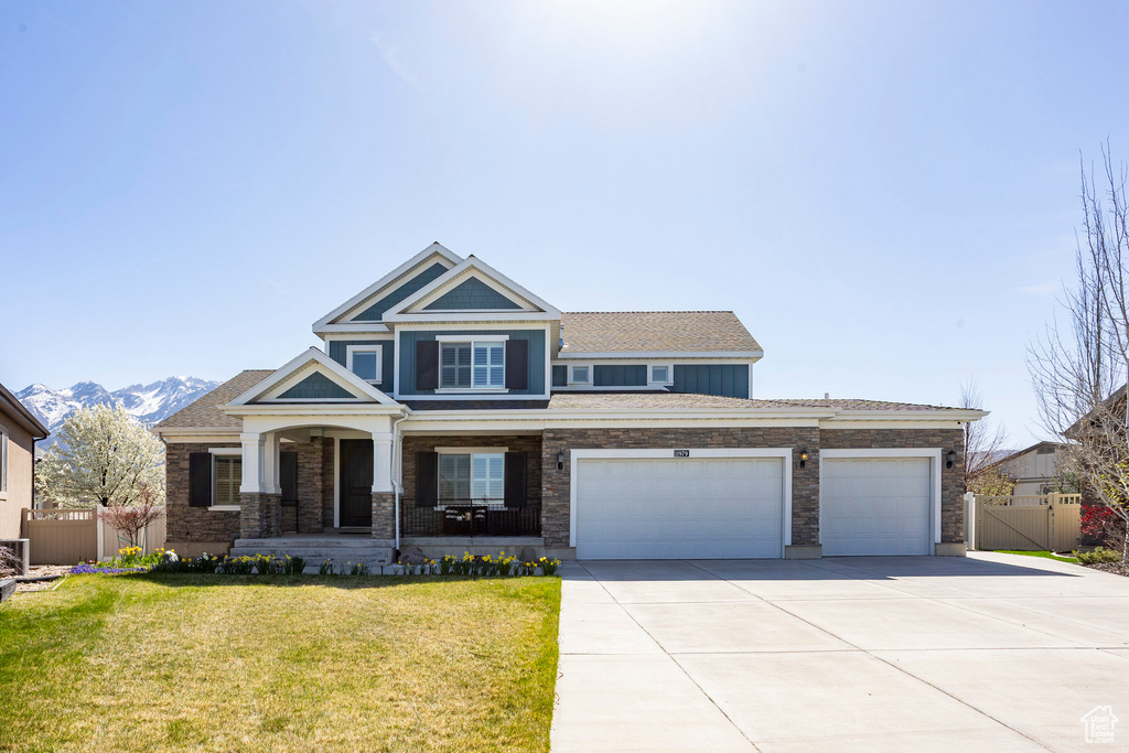 Craftsman inspired home with driveway, a front lawn, a porch, a garage, and fence