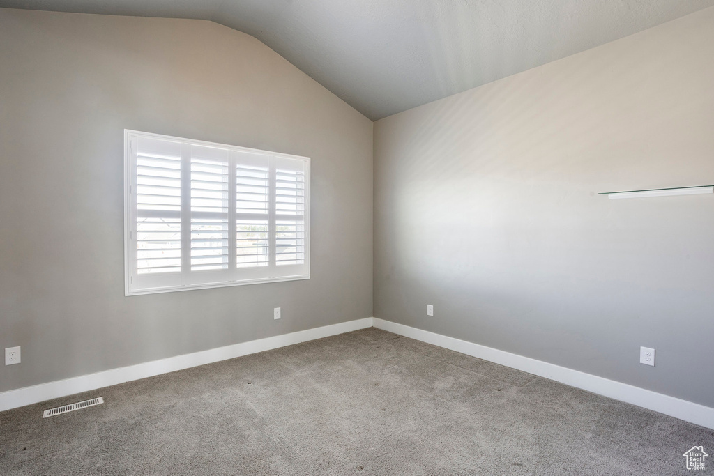 Unfurnished room with carpet, visible vents, baseboards, and vaulted ceiling
