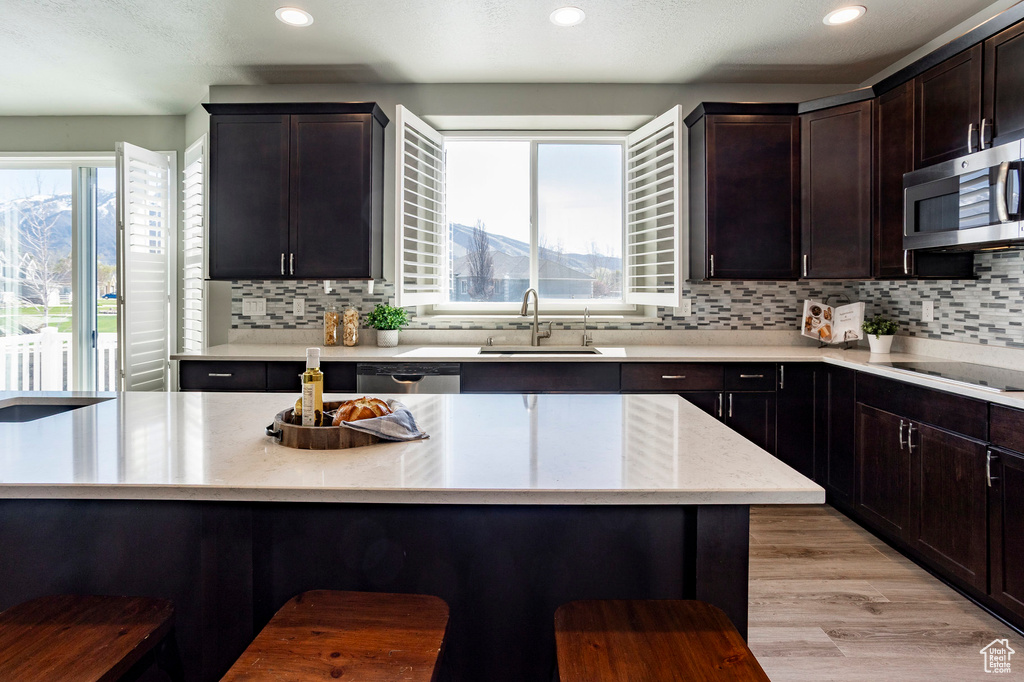Kitchen featuring a sink, stainless steel microwave, plenty of natural light, and black electric stovetop