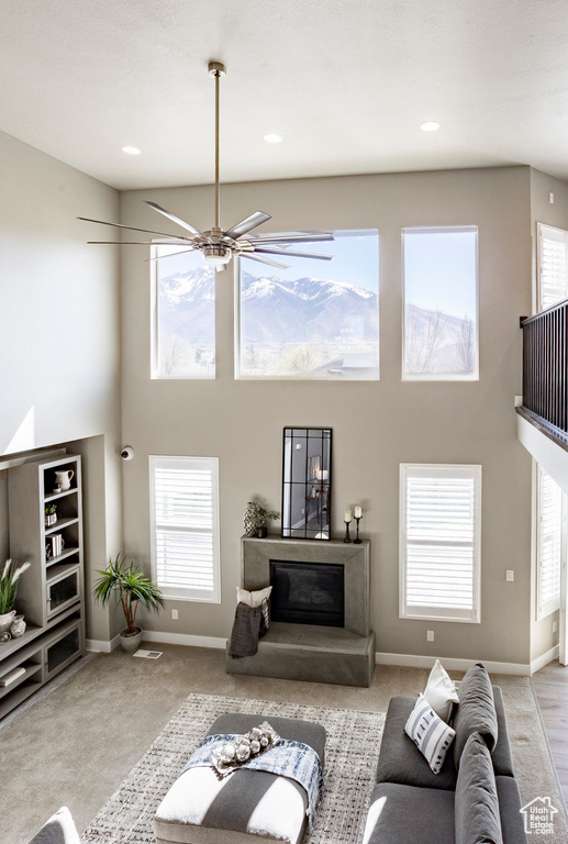 Carpeted living room featuring baseboards, a glass covered fireplace, and a towering ceiling