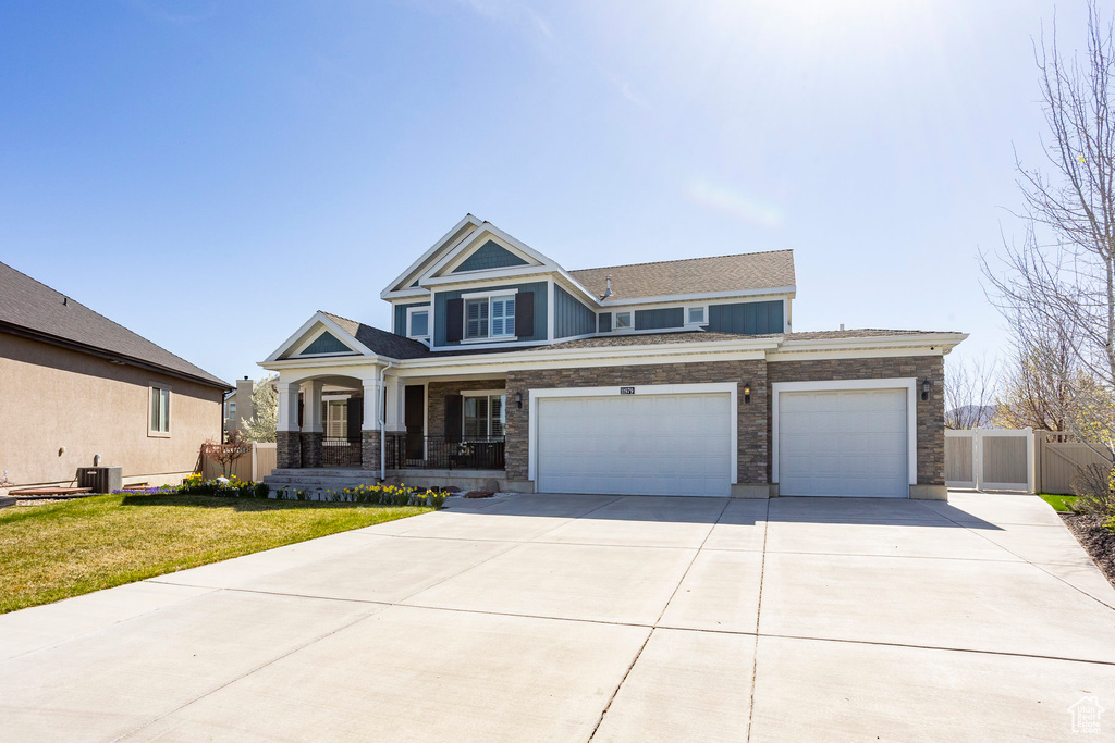 Craftsman inspired home with central AC, a front yard, an attached garage, fence, and driveway