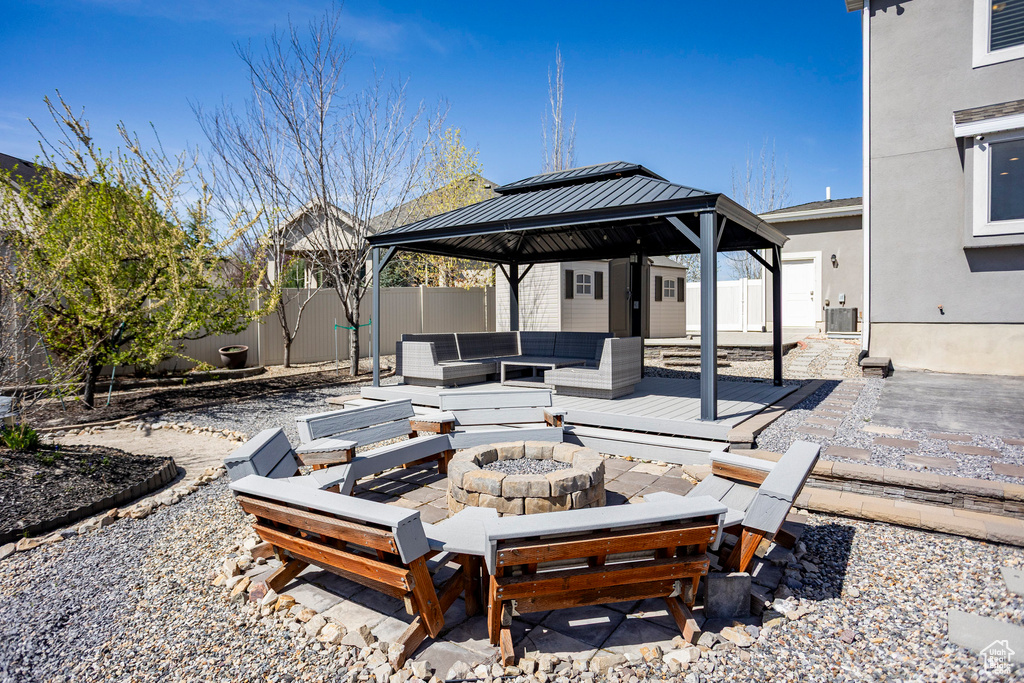 View of patio featuring an outdoor living space with a fire pit, a gazebo, cooling unit, and a fenced backyard