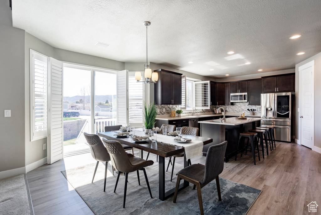 Dining room featuring recessed lighting, a notable chandelier, light wood-style floors, and a textured ceiling