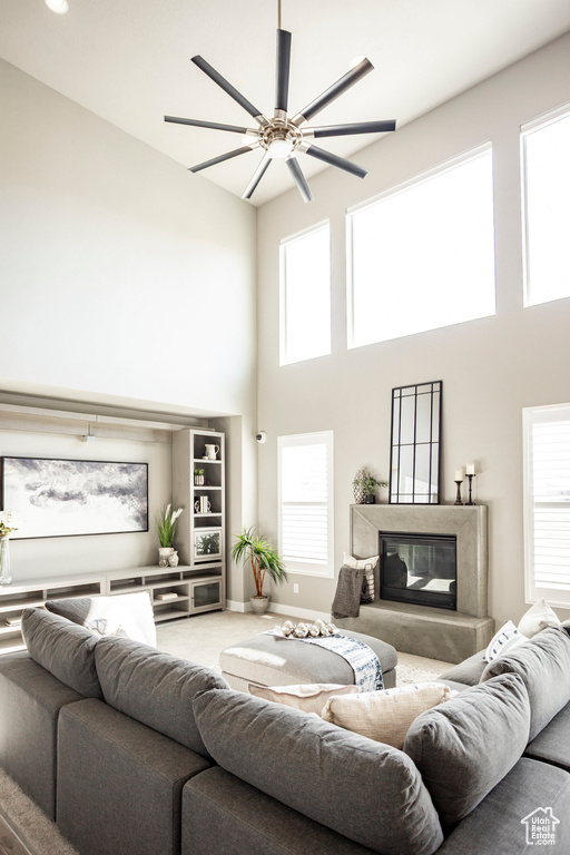 Living room featuring a high end fireplace, ceiling fan, a towering ceiling, and plenty of natural light