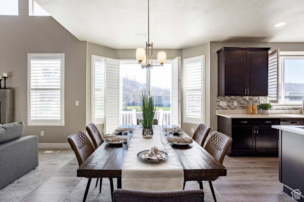 Dining area featuring a chandelier, a wealth of natural light, light wood-style floors, and a mountain view