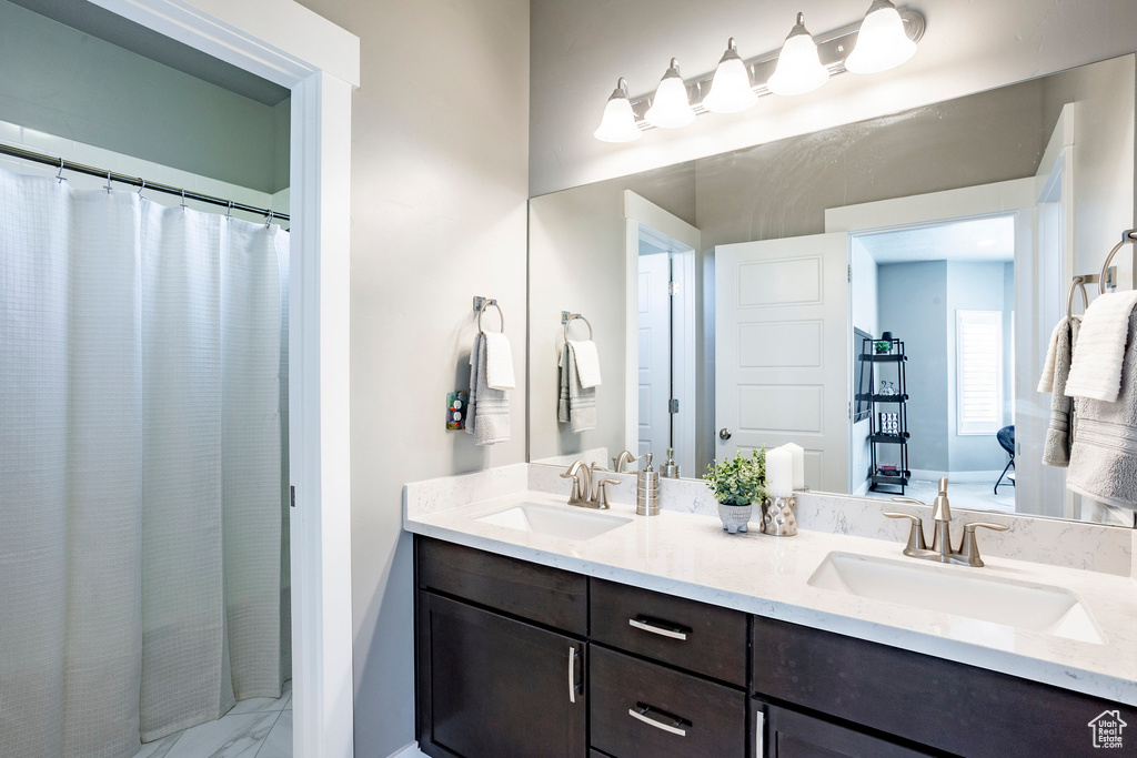 Bathroom with baseboards, double vanity, marble finish floor, and a sink