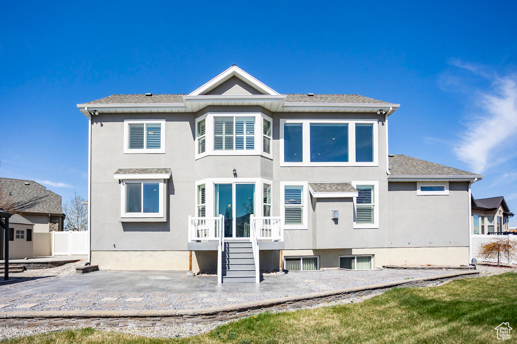 Rear view of house with a patio area, stucco siding, and fence