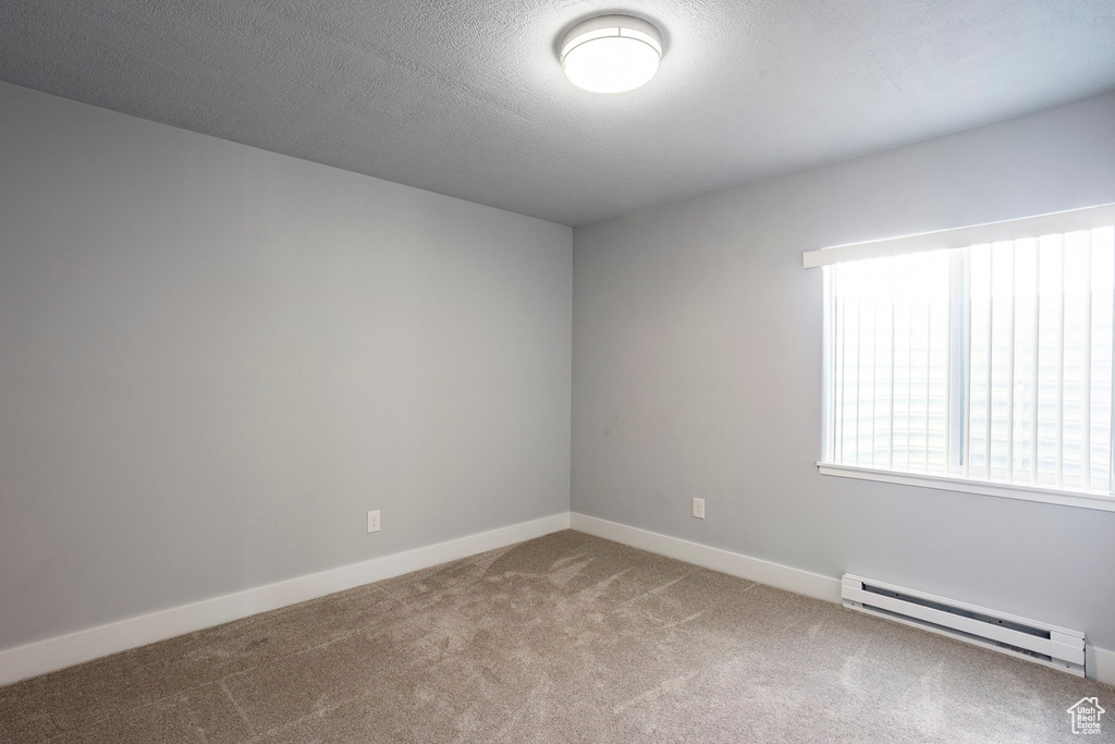 Empty room featuring a baseboard radiator, baseboards, and carpet