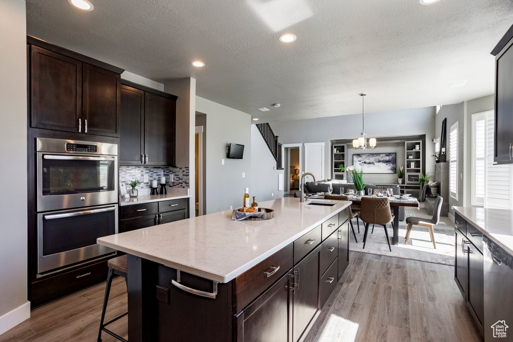Kitchen with open floor plan, a sink, dark brown cabinets, and stainless steel appliances