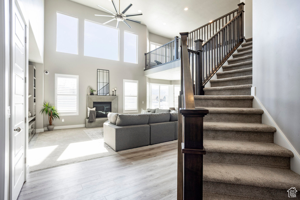 Interior space featuring baseboards, a high ceiling, stairs, a high end fireplace, and wood finished floors