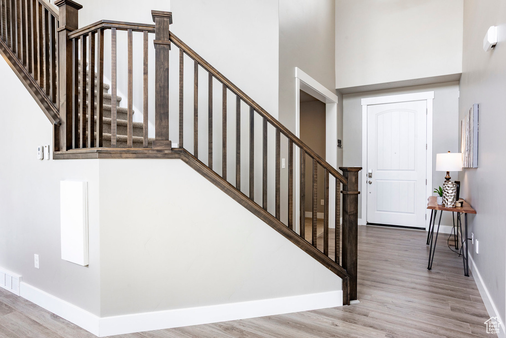 Stairs featuring a high ceiling, wood finished floors, and baseboards