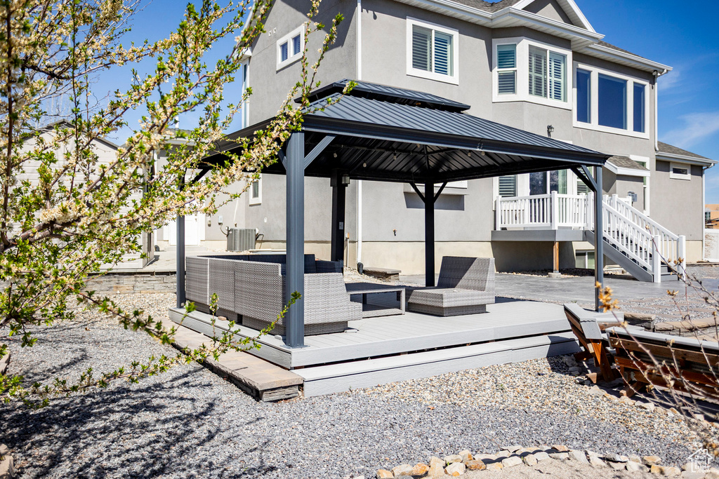 Back of property with metal roof, cooling unit, stucco siding, a wooden deck, and a standing seam roof