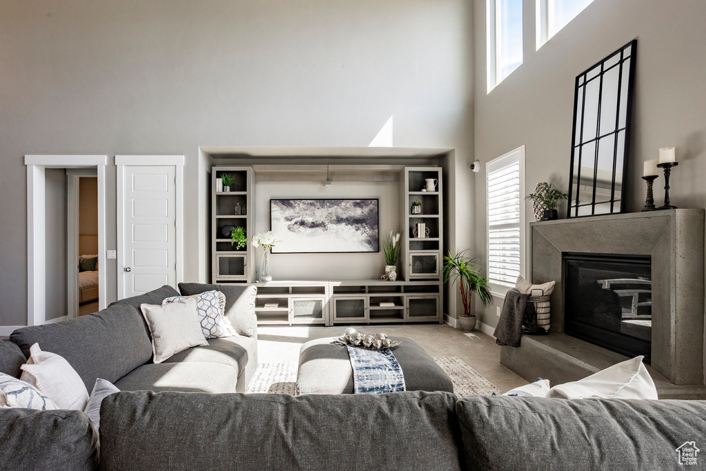 Living room featuring a premium fireplace, a high ceiling, baseboards, and carpet floors