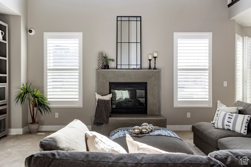 Carpeted living room featuring baseboards, a premium fireplace, and a healthy amount of sunlight