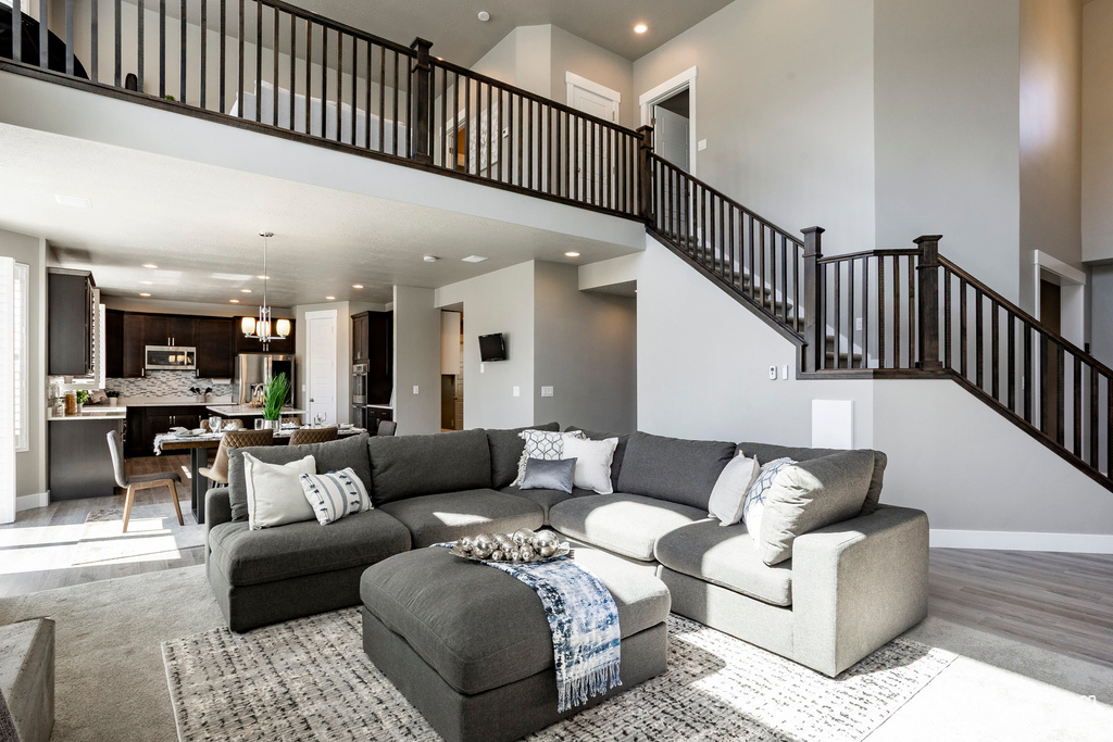 Living room featuring recessed lighting, a notable chandelier, light wood-style floors, and stairs
