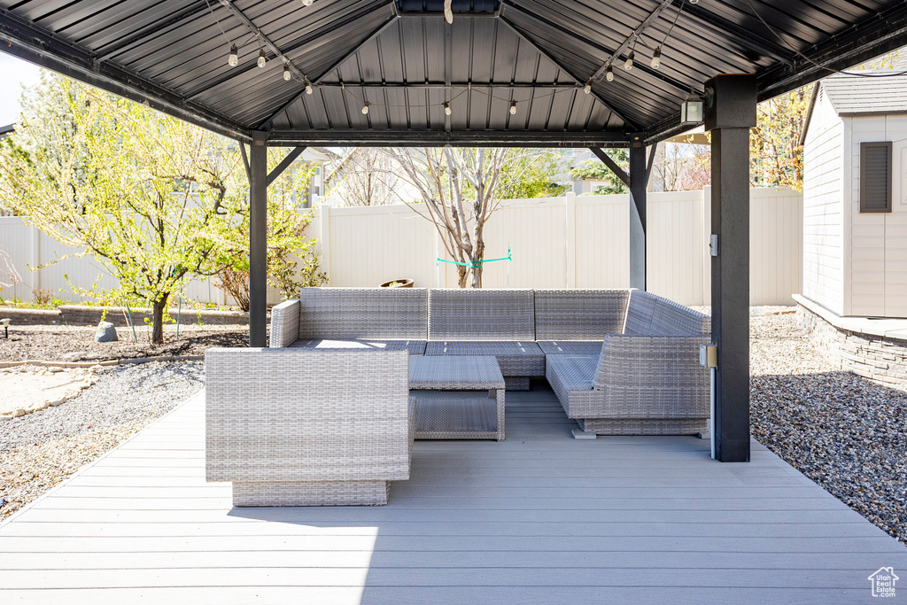 Wooden deck featuring a gazebo, an outdoor hangout area, and a fenced backyard