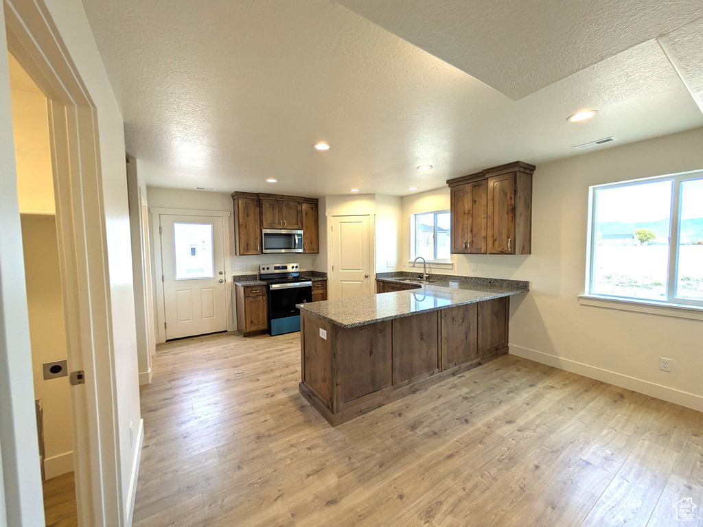 Kitchen featuring baseboards, electric range oven, a sink, a peninsula, and stainless steel microwave