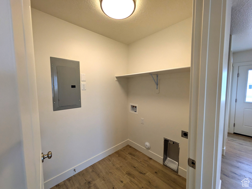 Laundry room with wood finished floors, hookup for a gas dryer, laundry area, and electric panel