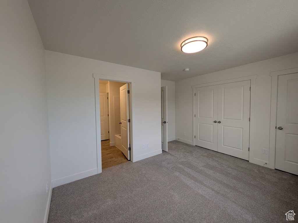 Unfurnished bedroom featuring ensuite bathroom, baseboards, and carpet floors