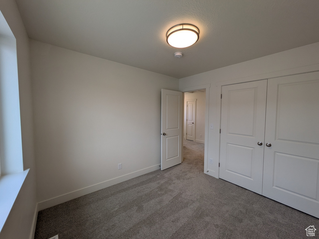 Unfurnished bedroom featuring a closet, carpet flooring, and baseboards
