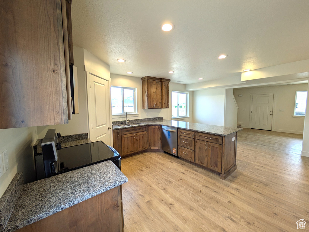 Kitchen featuring light wood-type flooring, a peninsula, recessed lighting, dishwasher, and a sink