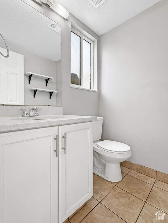 Bathroom featuring visible vents, toilet, a textured ceiling, vanity, and tile patterned flooring