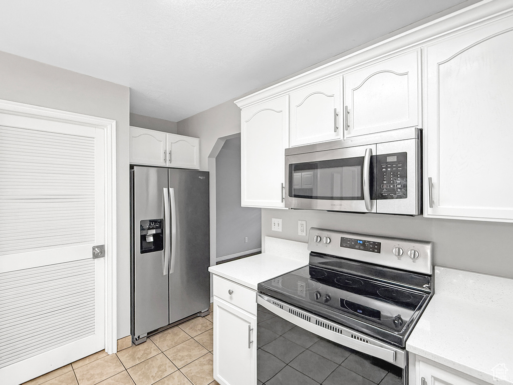 Kitchen featuring light tile patterned floors, white cabinets, and stainless steel appliances