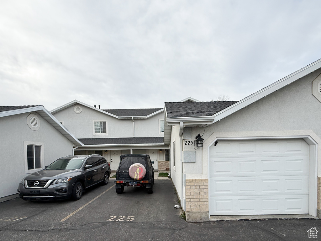 View of front of property with stucco siding and a shingled roof