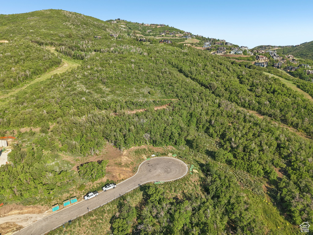 Aerial overview of property's location featuring a mountainous background and a heavily wooded area