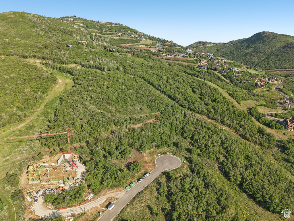 Aerial view of property and surrounding area with a forest and a mountain backdrop