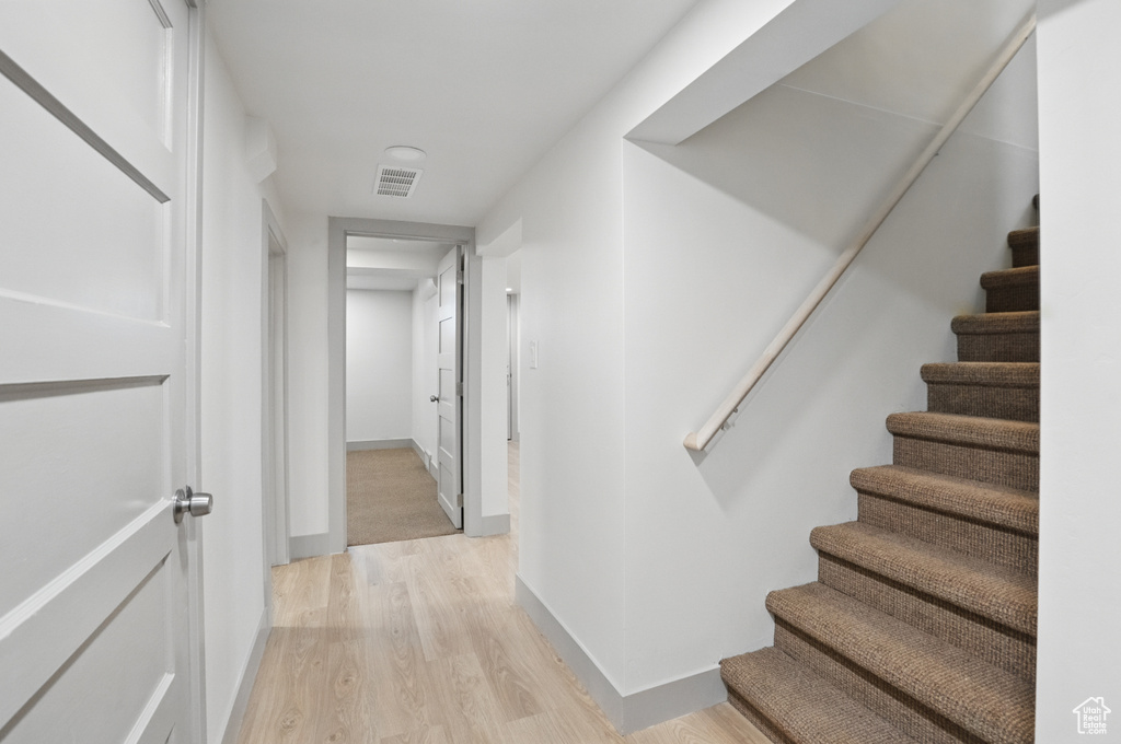 Hall featuring light wood finished floors, stairway, and baseboards