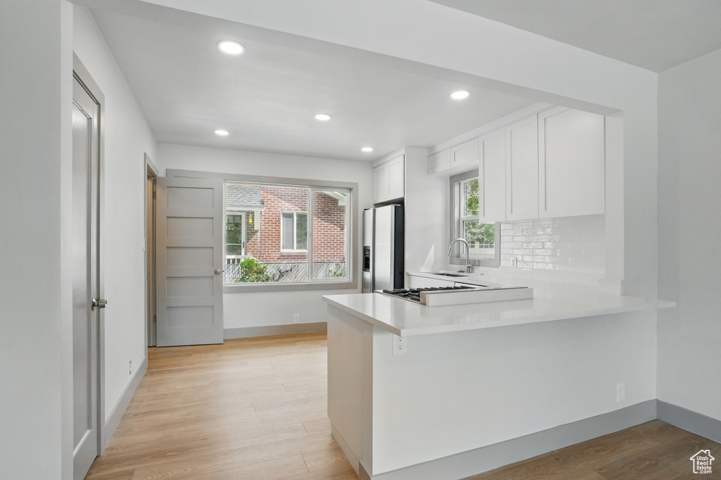 Kitchen with stainless steel fridge with ice dispenser, recessed lighting, white cabinets, light countertops, and decorative backsplash